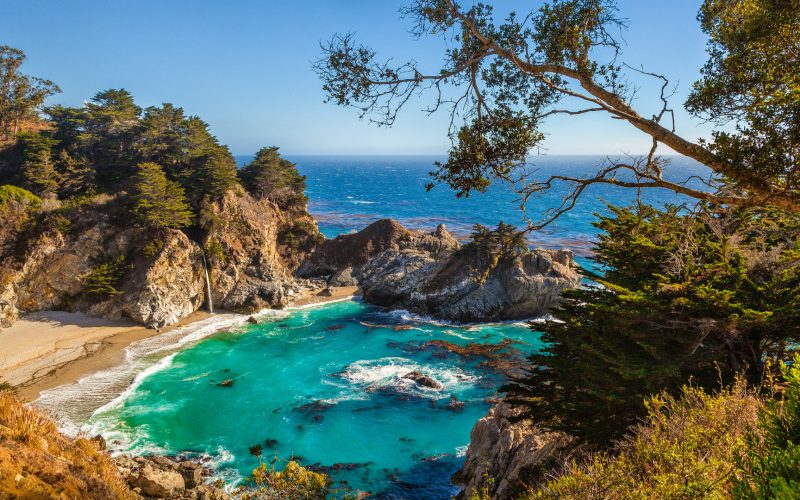 Classic postcard view of famous McWay Falls in scenic golden evening light at sunset on a beautiful sunny day with blue sky in summer, Julia Pfeiffer Burns State Park, Big Sur, California, USA