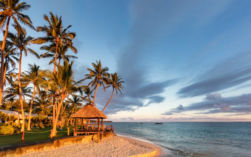 Beautiful sunset over a typical Fijian beach hut surrounded by palm trees at the coral coast beach in the south of Viti Levu, Fiji Island, Melanesia, Oceania.