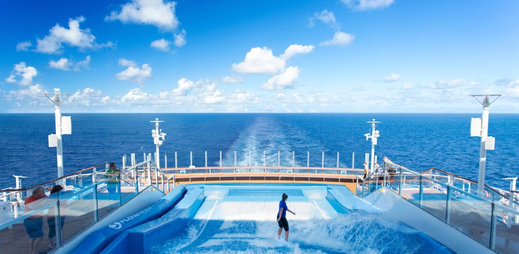 AN, Anthem of the Seas, FlowRider, POV facing rear of ship, woman surfing, people watching on side,